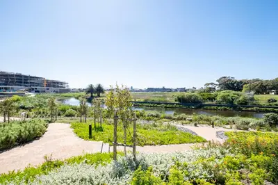 a garden with a river in the background at 622 Riverlands - Lux 2 Bedroom Apartment in Cape Town