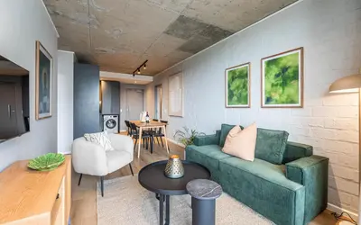 a living room with a green couch and a table at 622 Riverlands - Lux 2 Bedroom Apartment in Cape Town