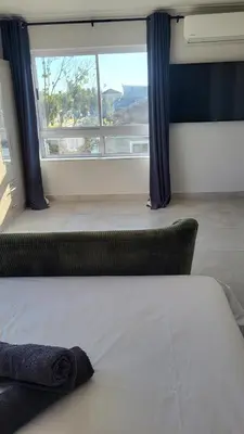 a bed in a room with a large window at Frankie's Nest in Cape Town