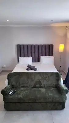 a bed with a couch in front of a bed at Frankie's Nest in Cape Town