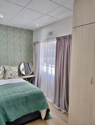 a bedroom with a bed and a large window at Finch Nest Self Catering in Paarl