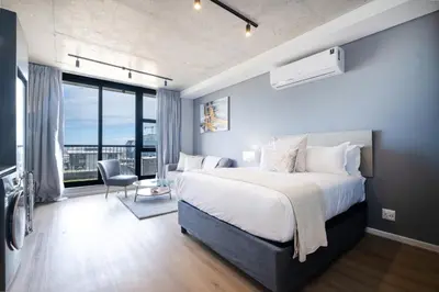 a bedroom with a large bed and a large window at 805 Riverlands - Lux Studio Apartment in Cape Town