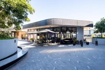 a building with a patio with tables and umbrellas at 805 Riverlands - Lux Studio Apartment in Cape Town