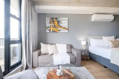a bedroom with a bed and a couch and a glass table at 805 Riverlands - Lux Studio Apartment in Cape Town