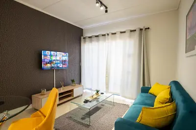 a living room with a blue couch and yellow chairs at #AlimamaSpaces The Manson's Fynbos in Cape Town