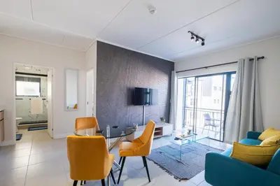 a living room with a blue couch and orange chairs at #AlimamaSpaces The Manson's Fynbos in Cape Town