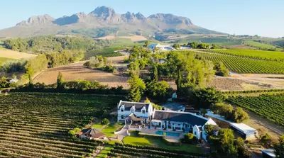 an aerial view of a house in a vineyard with mountains at Monkscowl Estate in Stellenbosch