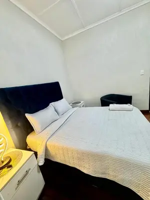 a bedroom with a large bed and a chair at kitty guest house in Bellville