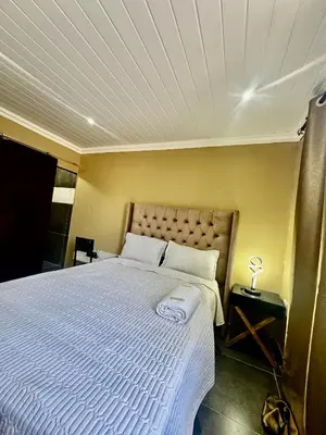 a bedroom with a large bed with a white comforter at kitty guest house in Bellville