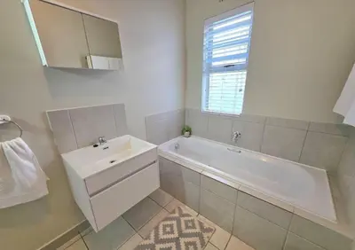 a bathroom with a tub and a sink and a mirror at 2 Bedroom house at Tweespruit - Pet friendly in Stellenbosch