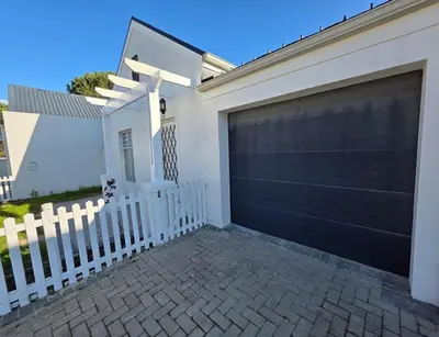 a garage door on a house with a white fence at 2 Bedroom house at Tweespruit - Pet friendly in Stellenbosch