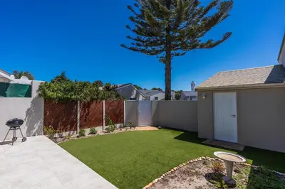 a small yard with a fence and a tree at The Woodbridge Hideaway in Cape Town