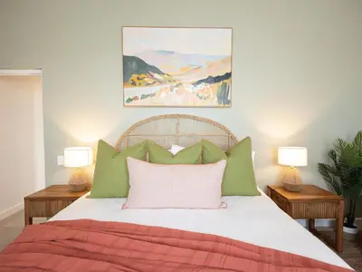a bedroom with a bed with green and pink pillows at Cornercade | Unit 1 in Hermanus