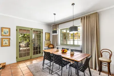 a dining room with a wooden table and chairs at Pepler House in Franschhoek