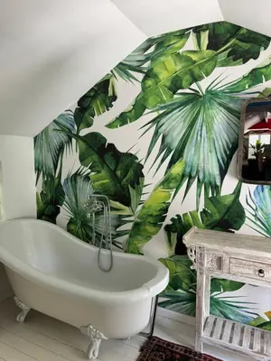 a bathroom with a bath tub and a tropical wallpaper at Pepler House in Franschhoek