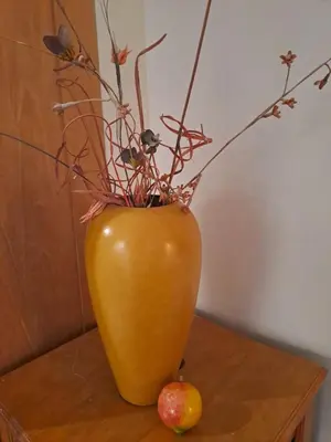 a yellow vase with branches and an apple on a table at Boutique Inn - Quintessence in Gordonʼs Bay