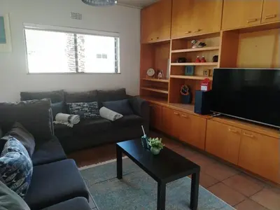 a living room with a couch and a flat screen tv at Art House on Main in Hermanus