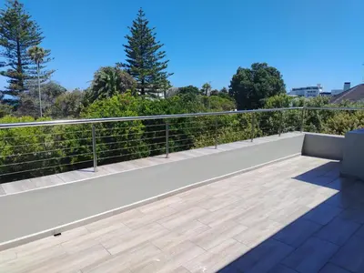 a balcony with a white railing and trees at Art House on Main in Hermanus