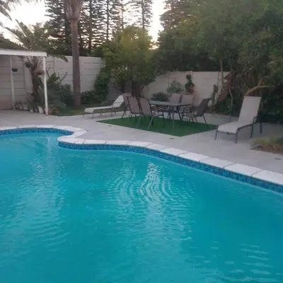 a blue swimming pool with chairs and a table at Capetown Adilo Villa in Cape Town