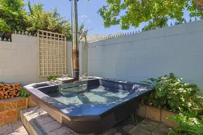 a jacuzzi tub in a backyard with a fence at Herringbone with Wood-Fired Hot Tub in Hermanus