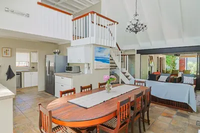 a kitchen and dining room with a table and chairs at Herringbone with Wood-Fired Hot Tub in Hermanus