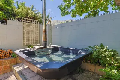 a jacuzzi tub in a backyard with a fence at Herringbone with Wood-Fired Hot Tub in Hermanus