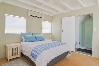a bedroom with a bed with blue pillows on it at Herringbone with Wood-Fired Hot Tub in Hermanus