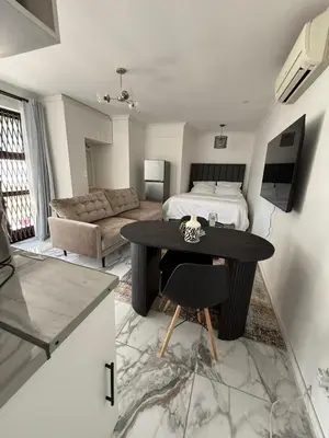 a bedroom with a bed and a table and a couch at Furnished apartment in Capetown in Ottery