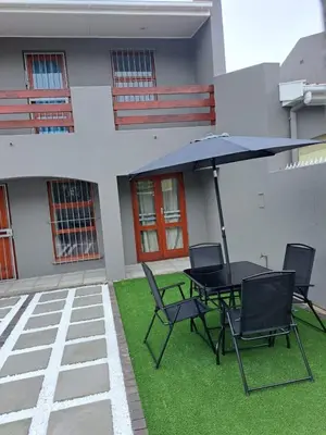 a patio with a table and chairs and an umbrella at Capetown Adilo Villa 2 in Cape Town