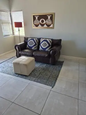 a living room with a leather couch and a stool at Secure Modern stay at 41 on Kennington in Parklands