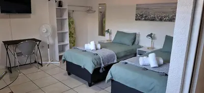 a room with two twin beds and a fan at Cozy Quarters Self-Catering Accommodation in Bellville