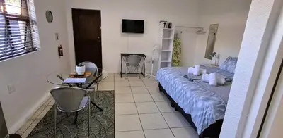 a bedroom with a bed and a table and a television at Cozy Quarters Self-Catering Accommodation in Bellville