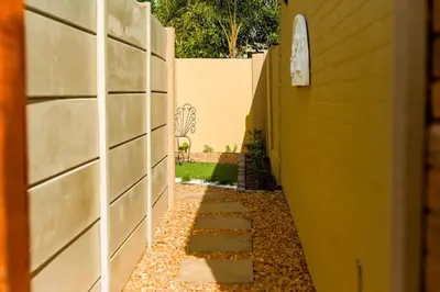 an alley way with a yellow wall and a sidewalk at Velvet & Bloom Cottage in Durbanville in Oakdale