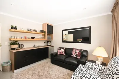 a living room with a couch and a television at Velvet & Bloom Cottage in Durbanville in Oakdale