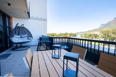 a balcony with chairs and a swing and a table at 312 Riverlands - Lux 2 bedroom Apartment in Cape Town