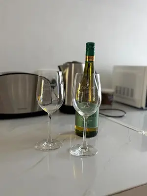 a bottle of wine and two wine glasses on a counter at Le Grec Wine Tram Apartment #2 in Franschhoek