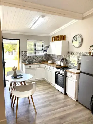 a kitchen with white appliances and a table and a table and chairs at Living Lite in Kleinmond