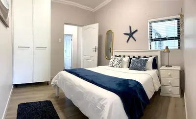 a bedroom with a large white bed and a mirror at Living Lite in Kleinmond