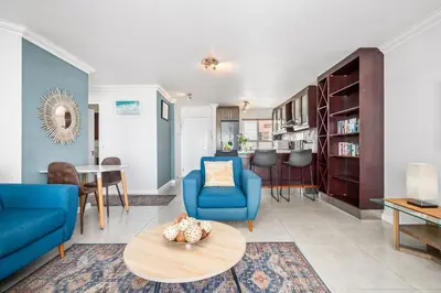 a living room with blue chairs and a table at Sea Spray Views in Cape Town