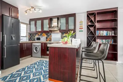 a kitchen with a counter and some chairs in it at Sea Spray Views in Cape Town