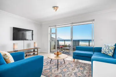 a living room with blue couches and a tv at Sea Spray Views in Cape Town