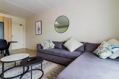 a living room with a purple couch and a mirror at #AlimamaSpaces Thando's Fynbos in Cape Town