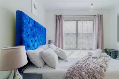 a white bed with a blue headboard and white pillows at #AlimamaSpaces Thando's Fynbos in Cape Town