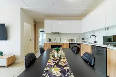 a kitchen with a black table and chairs in a kitchen at #AlimamaSpaces Thando's Fynbos in Cape Town