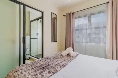 a bedroom with a large white bed with a window at #AlimamaSpaces Thando's Fynbos in Cape Town