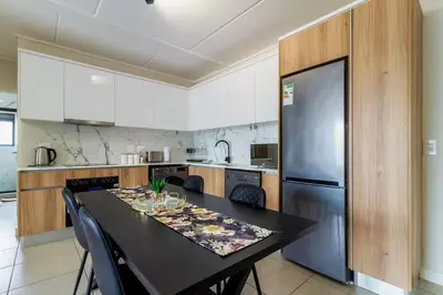 a kitchen with a black table and a refrigerator at #AlimamaSpaces Thando's Fynbos in Cape Town