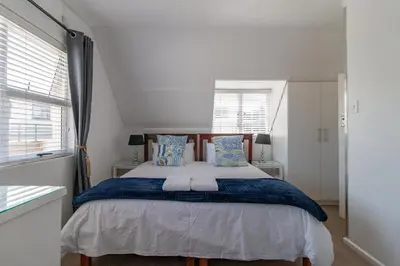 a bedroom with a large bed with blue and white pillows at TwentyFour 17 Inn in Hermanus