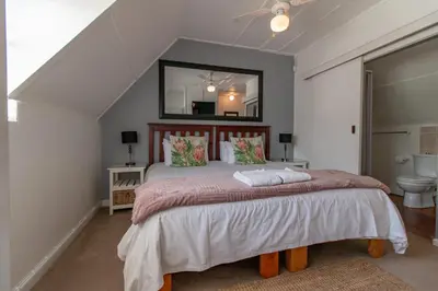 a bedroom with a large bed and a mirror at TwentyFour 17 Inn in Hermanus