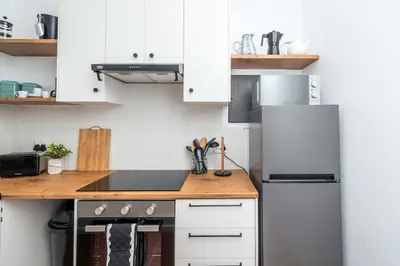 a kitchen with white cabinets and a refrigerator at First floor Claremont Studio apartment in Cape Town