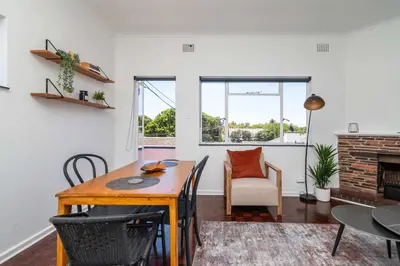 a living room with a table and chairs and a fireplace at First floor Claremont Studio apartment in Cape Town